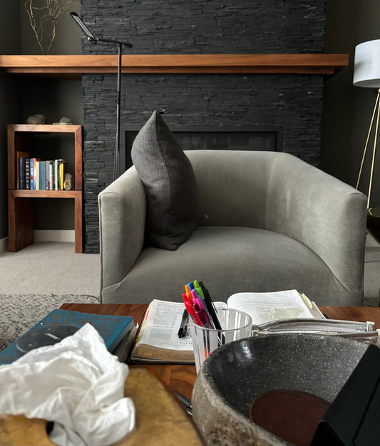 armchair in a living room next to coffee table with bible study items on it